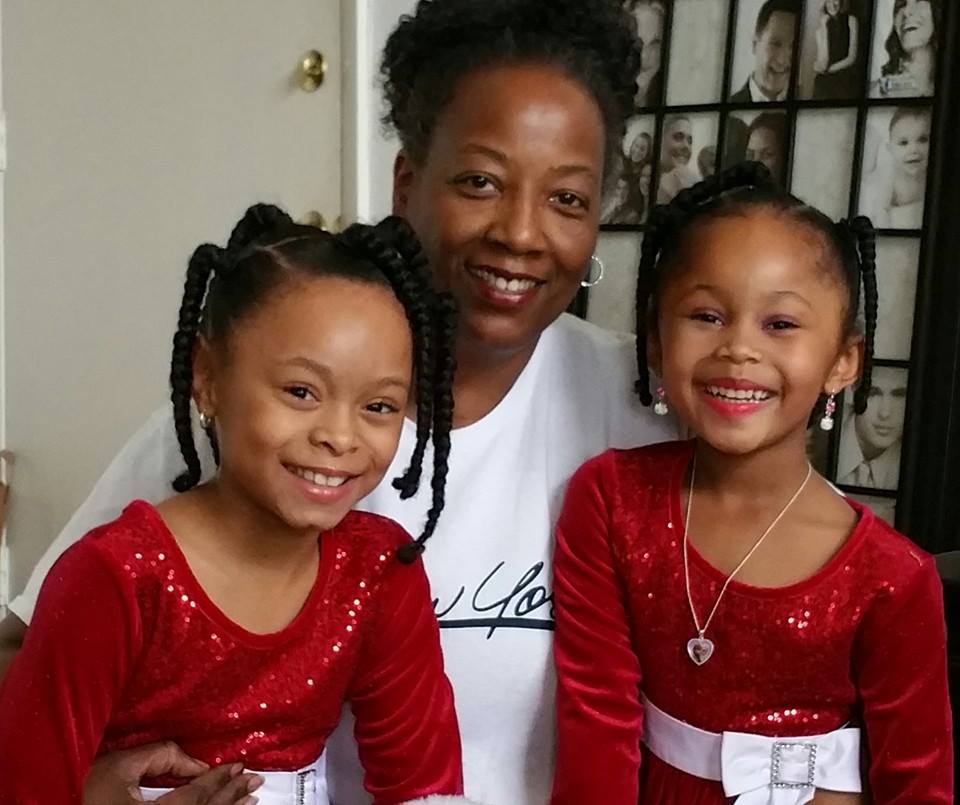 Marilyn Wilson smiling with two young girls in matching red dresses